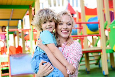 selective focus of happy mother holding adorable little son on hands at playground
