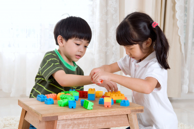 Asian kids piling up building blocks